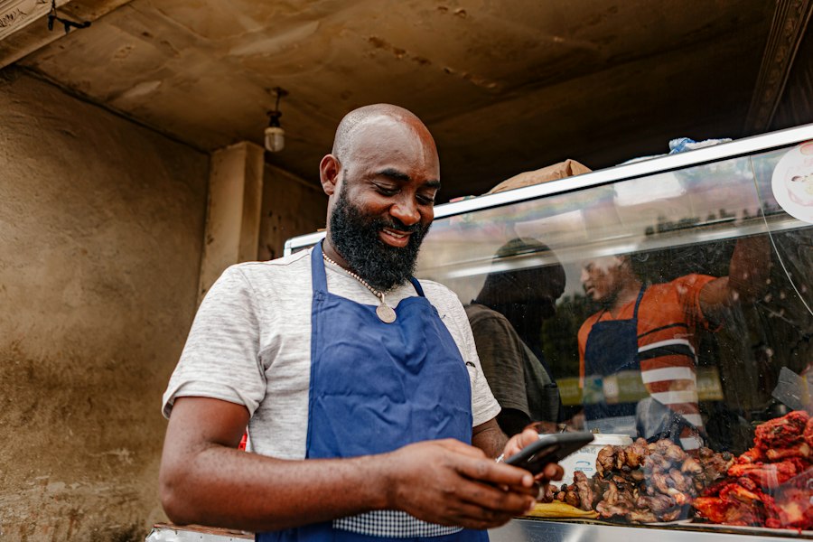 A shop owner in an apron checking his phone